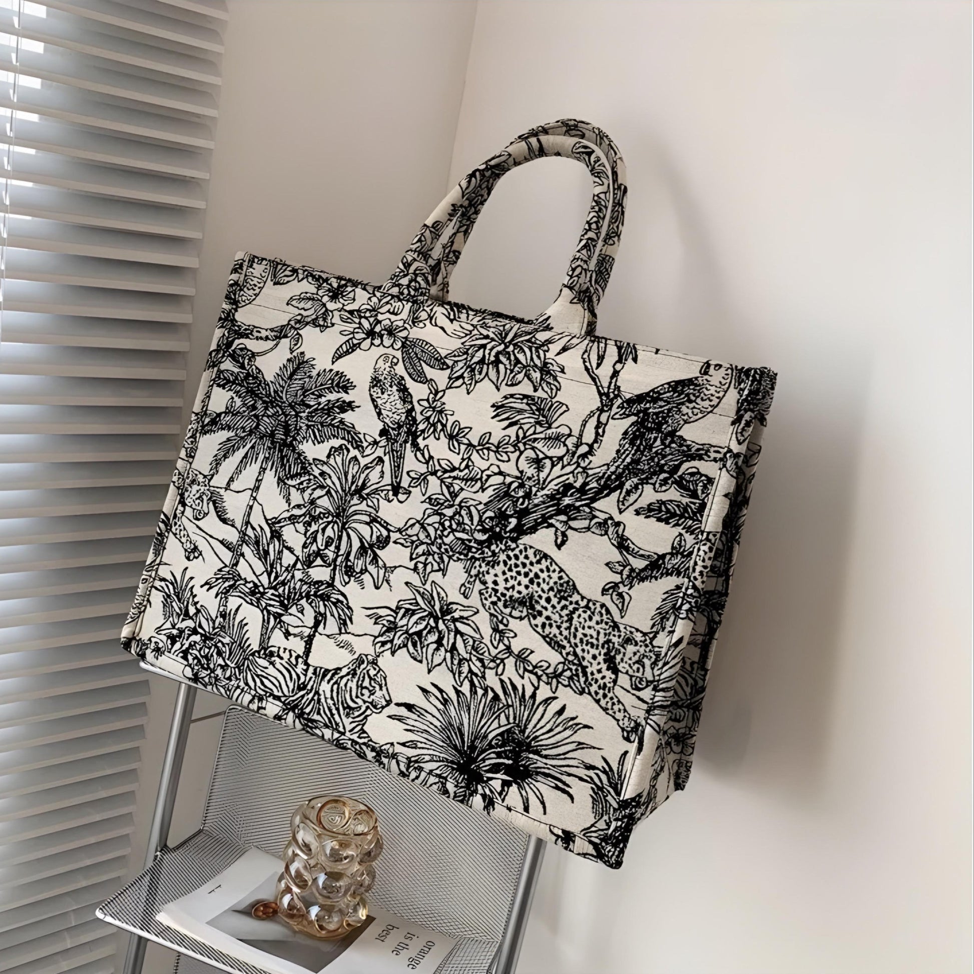 A white canvas tote bag with a black nature-themed print, displayed in a home setting.